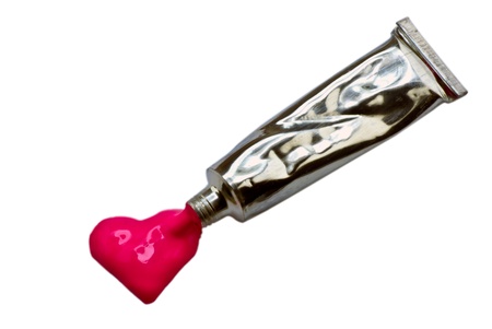 Spilling color tube, heart shape formed, on white backgroundの写真素材