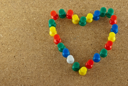 Colorful pins stick on corkboard in heart shapeの写真素材