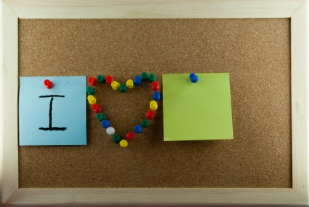 Post-it note and heart shape pins on corkboardの写真素材