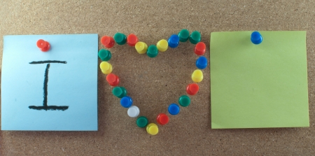 Post-it note and heart shape pins on corkboard - close upの写真素材