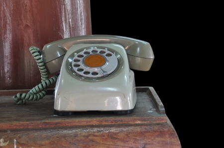 Classic telephone on wooden table in front of black backgroundの写真素材