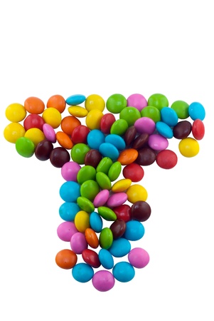 Colorful candies lay in letter T in front of white backgroundの写真素材