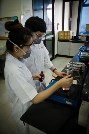 Two young researchers using an apparatus in a laboratory.のeditorial素材