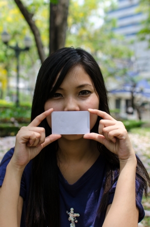 Lovely Chinese girl with blank card in the gradenの写真素材