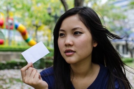 Lovely Chinese girl with blank card in the gradenの写真素材