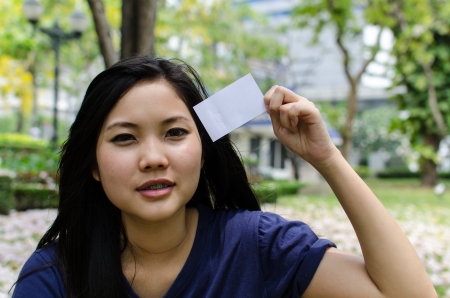 Lovely Chinese girl with blank card in the gradenの写真素材