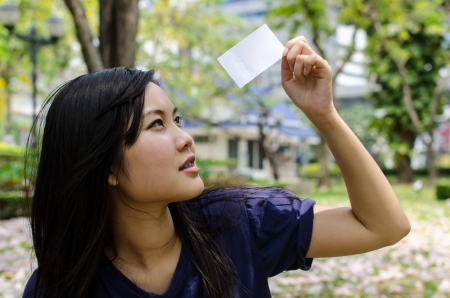 Lovely Chinese girl with blank card in the gradenの写真素材