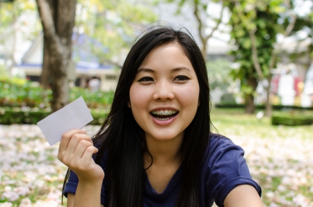 Lovely Chinese girl with blank card in the gradenの写真素材