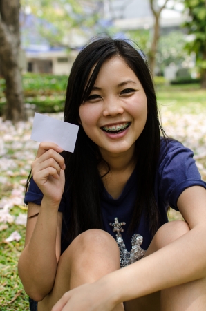 Lovely Chinese girl with blank card in the gradenの写真素材