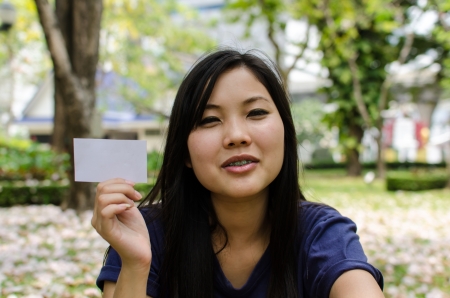 Lovely Chinese girl with blank card in the gradenの写真素材