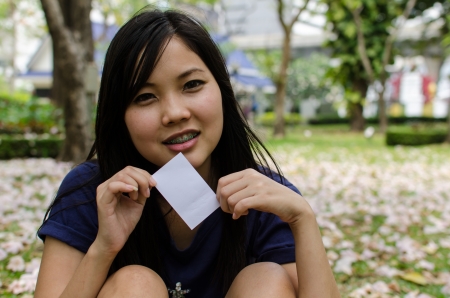 Lovely Chinese girl with blank card in the gradenの写真素材