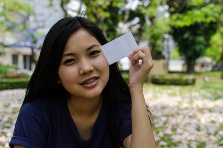 Lovely Chinese girl with blank card in the gradenの写真素材