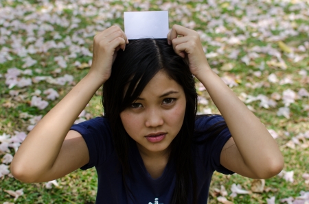 Lovely Chinese girl with blank card in the gradenの写真素材