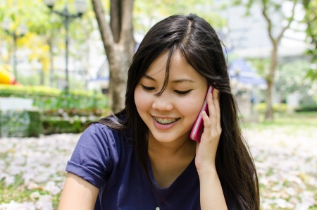 Lovely Chinese girl using cell phone in the gradenの写真素材