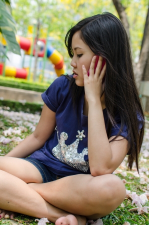 Lovely Chinese girl using cell phone in the gradenの写真素材