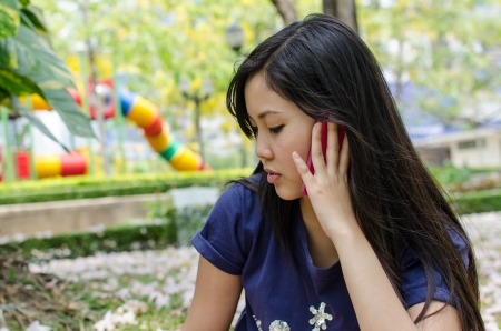 Lovely Chinese girl using cell phone in the gradenの写真素材