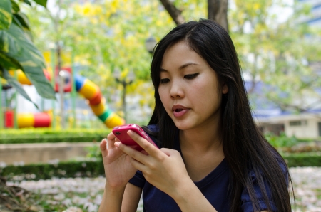 Lovely Chinese girl using cell phone in the gradenの写真素材