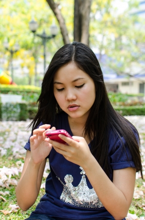 Lovely Chinese girl using cell phone in the gradenの写真素材