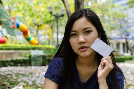 Lovely Chinese girl with blank card in the gradenの写真素材