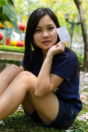 Lovely Chinese girl with blank card in the gradenの写真素材