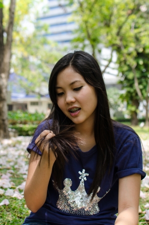 Lovely Chinese girl look at her hair in the gradenの写真素材