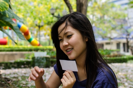 Lovely Chinese girl with blank card in the gradenの写真素材