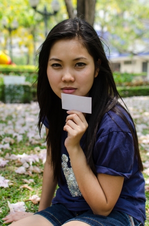 Lovely Chinese girl with blank card in the gradenの写真素材