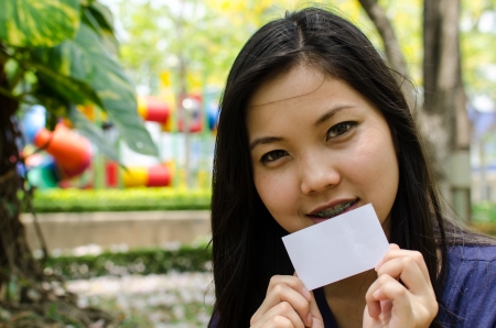 Lovely Chinese girl with blank card in the gradenの写真素材