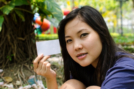 Lovely Chinese girl with blank card in the gradenの写真素材