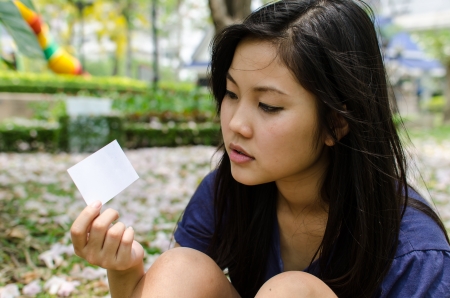 Lovely Chinese girl with blank card in the gradenの写真素材