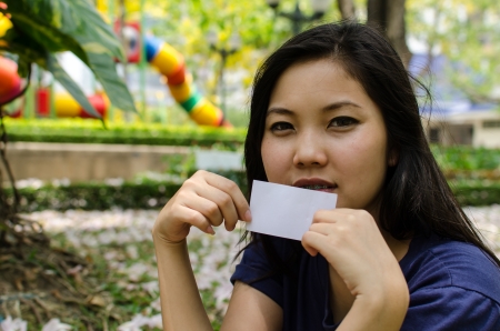 Lovely Chinese girl with blank card in the gradenの写真素材