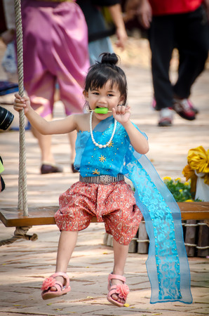 a little thai girl on a swing, eating ice-creamのeditorial素材