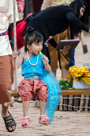a little thai girl on a swing, eating ice-creamのeditorial素材