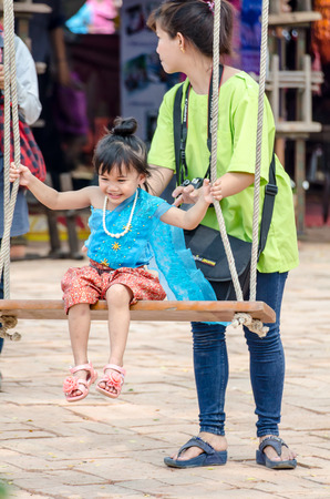 young adorable mother swinging with daughterのeditorial素材