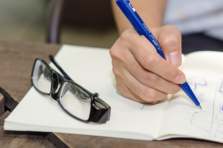 Close-up of a young girl writing into her diary, in the parkの写真素材