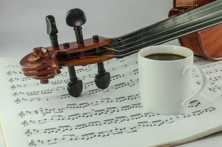 Closeup of violin and cup of coffee on music sheet の写真素材