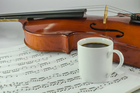 Closeup of violin and cup of coffee on music sheet の写真素材