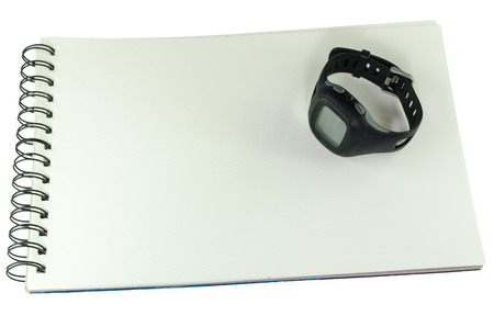 Black wrist watch lying open on a spiral bound blank white sketch book, high angle view isolated on whiteの写真素材
