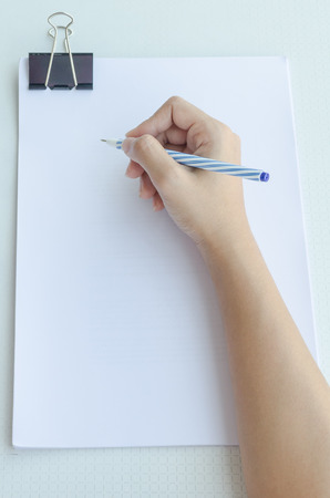 Close-up of a woman writing into blank paper with binder clipの写真素材