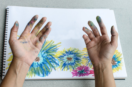 Hand with stained pastel in front of the colorful flower paintingの写真素材