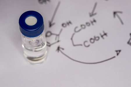 Sample vial on paper with handwritten chemical formulaの写真素材