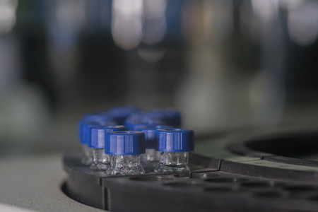 Sample vials in line waiting for analysis in front of light bokehの写真素材