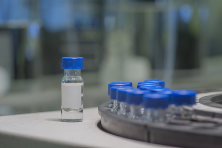 Sample vials in line waiting for analysis - one vial out of trayの写真素材