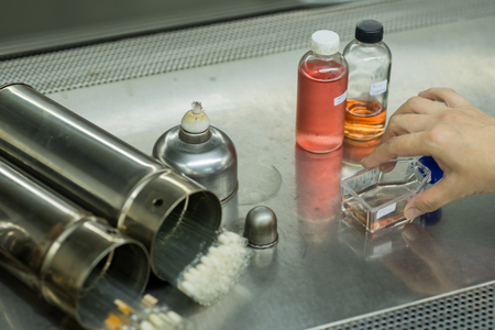 Close up of hand picking up glass container among other laboratory supplies on stainless steel shelvesの写真素材