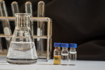 Blue cap vials and out of focus laboratory glassware containing chemicals in science researchの写真素材