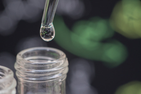 Reflection of chemical formular in water drop on test tube in front of blur chemical formulaの写真素材