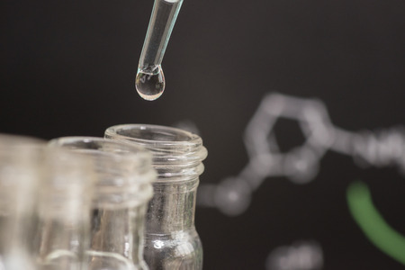 Reflection of chemical formular in water drop on test tube in front of blur chemical formulaの写真素材
