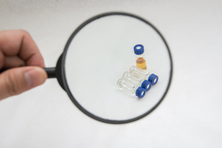Handing magnify glass on sample vialの写真素材