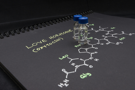 Close-up blue cap sample vial on paper with chemical formula of Oxytocin (love hormone)の写真素材