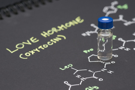 Close-up blue cap sample vial on paper with chemical formula of Oxytocin (love hormone)の写真素材